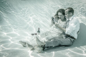 a man and woman sitting in the water in wedding